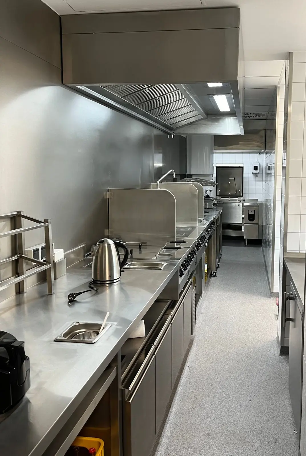 Gastronomieküche mit Edelstahl-Arbeitsflächen und Dunstabzugshaube