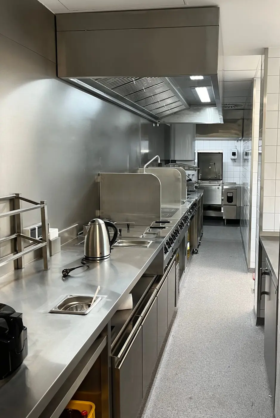 Gastronomieküche mit Edelstahl-Arbeitsflächen und Dunstabzugshaube